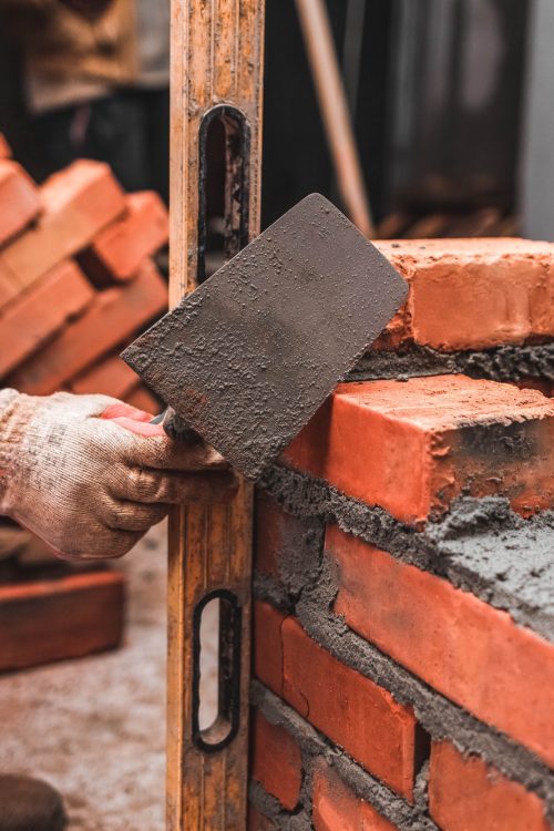 Bricklayer puts bricks to make a wall