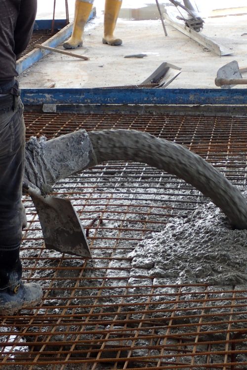 Construction worker pouring concrete for a building floor slab