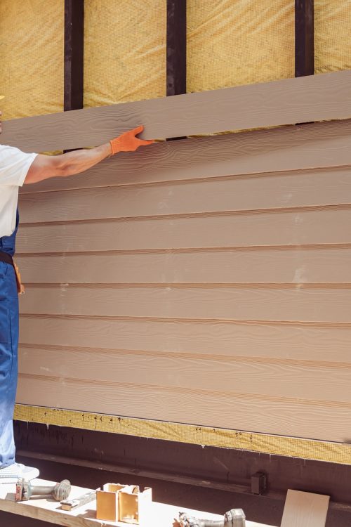 Handsome man builder building cabin at construction site