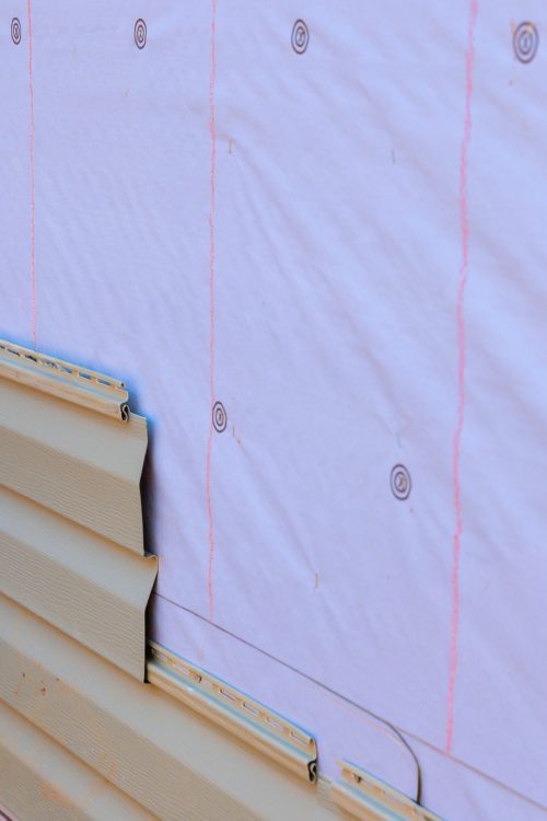 In process of installing vinyl siding on new home facade, a handyman installs vinyl PVC siding
